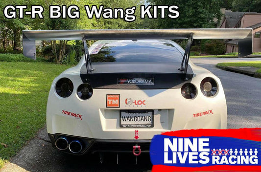 A white Nissan GT-R, equipped with the GT-R Big Wang Kit '07-22 for optimal downforce adjustments, is parked on a residential street. Sponsor stickers include Yokohama and Tire Rack. The license plate reads "WANGGANG," with "Big Wang GT3" and "9livesracing" prominently displayed.