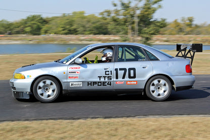 Image of the 9livesracing Audi S4 (b5) 1998-2001 big wang kit. The wing features a large white spoiler with black mounts for maximum downforce and low drag. The brown, partially-damaged rear portion of the car is shown. "Pre-order pricing" text is in the bottom left corner. Nine Lives Racing logo in the bottom right.