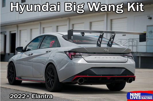 A silver Hyundai Elantra sedan shown from the rear three-quarter angle with a large rear wing, black wheels, and red accent trim. The image has text overlays reading 'Hyundai Big Wang Kit' at the top and '2022+ Elantra' at the bottom left, with a 'NINE LIVES RACING' logo at the bottom right.