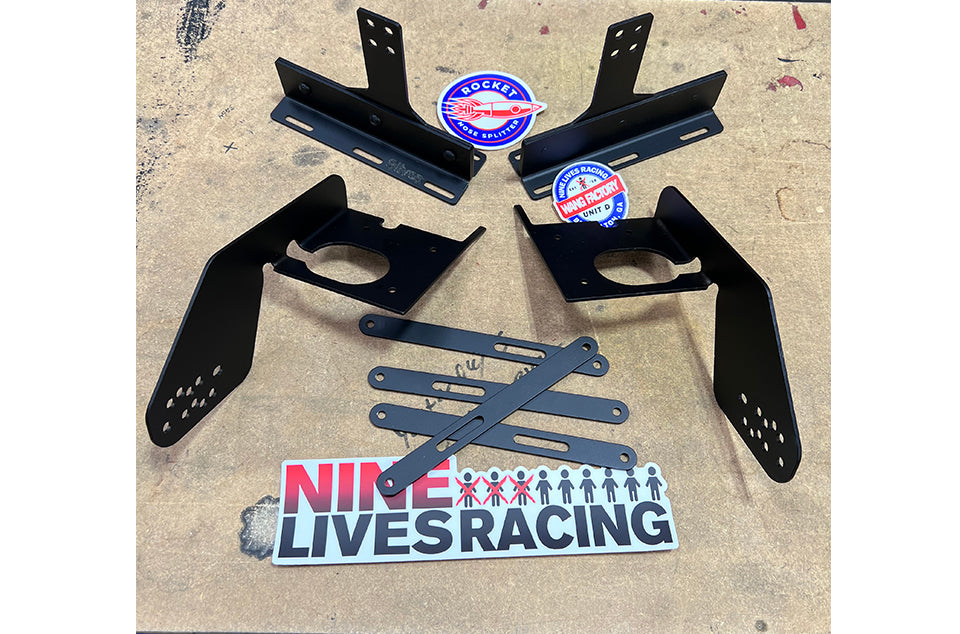 A set of black metal brackets and additional mounting components for the Corvette splitter kit C7 with Sturdy Boii mounts are laid out on a surface. The image also includes two round stickers featuring the 9livesracing logo and a rectangular sticker that reads "NINE LIVES RACING" in red and black text.