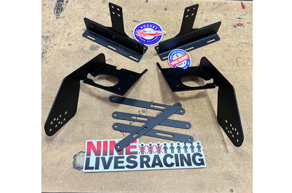 A set of black metal brackets and additional mounting components for the Corvette splitter kit C7 with Sturdy Boii mounts are laid out on a surface. The image also includes two round stickers featuring the 9livesracing logo and a rectangular sticker that reads "NINE LIVES RACING" in red and black text.