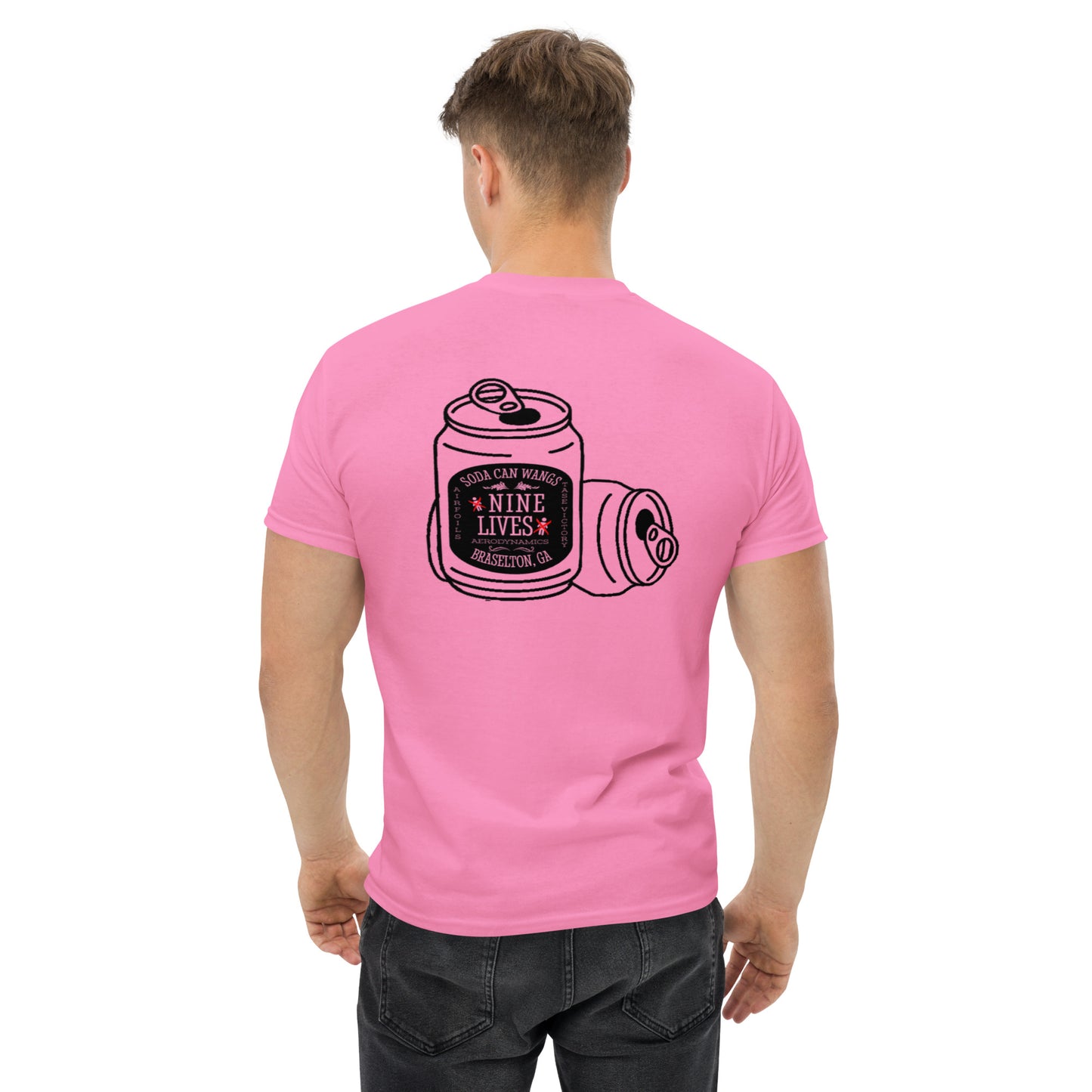 A person with short hair is facing away, wearing the Men's Soda Can Wang t-shirt by Nine Lives Racing in pink. The 100% cotton T-shirt showcases a black line drawing of a soda can labeled "Nine Lives" and "Soda Can Mafia," adorned with additional small text and decorative elements. The individual has effortlessly paired it with black jeans, perfectly embodying layered streetwear outfits.