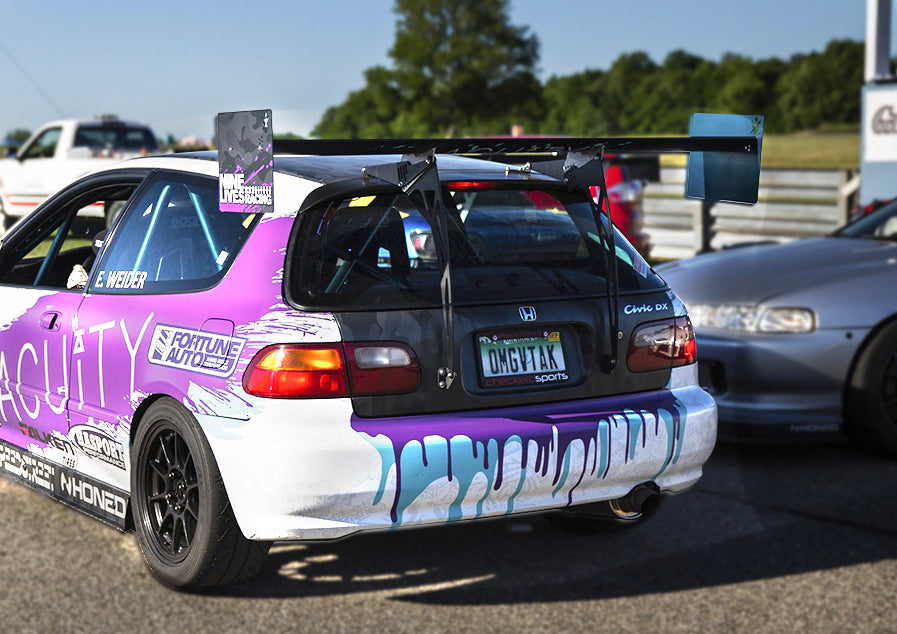 A modified hatchback car with a white and purple color scheme, featuring 9livesracing Universal Hatchback Wing Pylons with an adjustable mount angle and customized decals, is parked next to another car. The license plate reads "ONGTAX." The car has noticeable graffiti-like paint drips on the back and side, with "ACUITY" written on the side.