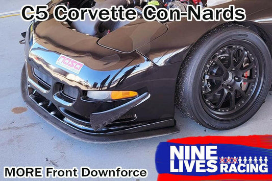 A close-up of the front end of a black C5 Corvette equipped with the C5 Corvette Car-Nards from Nine Lives Racing. The car boasts a front splitter and a "NASA" decal. The image highlights the increased front balance provided by the High Downforce kits and features the "Nine Lives Racing" logo in the bottom right corner.