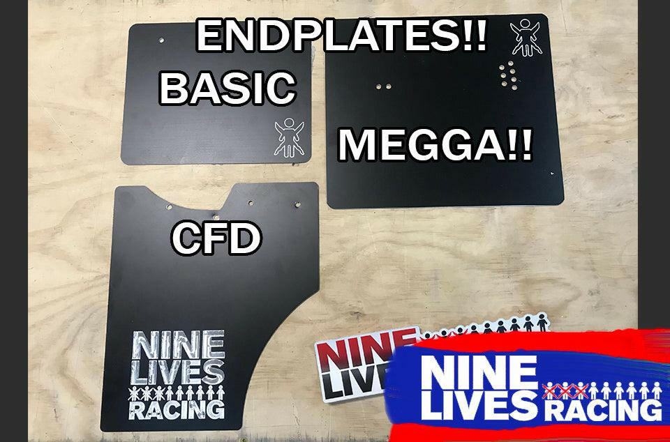 Three black car endplates labeled "Basic," "Megga!!," and "CFD" are displayed on a wooden surface. A "9livesracing" logo sticker is placed below them, accompanied by additional stickers to the right on a blue and red background. These stickers highlight the impressive 15.2:1 lift to drag ratio of The Builder's Big Wáng - Spec Your Own Size from 9livesracing's GT3 performance products.
