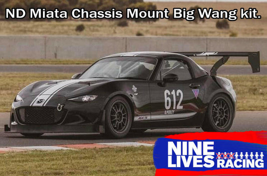 A black ND Miata race car, numbered 612, is showcased on a racetrack, equipped with a remarkable Big Chassis Mount Wang for enhanced down-force. The top of the image displays the text "Miata Big Chassis mount Wang Kit 2016+ ND," while the bottom right corner features the "9livesracing" logo.