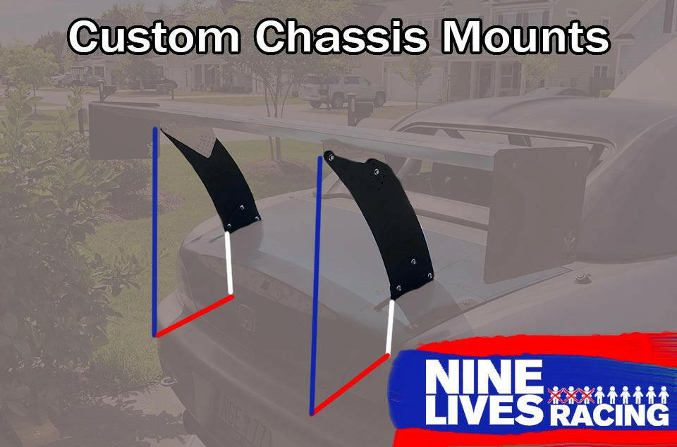 A car is equipped with a large rear spoiler featuring Custom Chassis Mount kits, designed for an optimal wing Angle Of Attack (AOA). The text "Custom Chassis Mounts" is displayed at the top of the image. In the bottom right corner, there is a logo featuring the text "9livesracing" with a graphic of nine human figures above it.