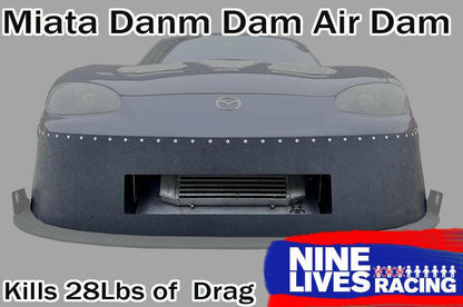 A front view of a grey Mazda Miata with an aftermarket air dam attached. Text at the top reads "Miata Damn Dam '90-05 NA/NB" and at the bottom reads "Kills 28Lbs of Drag". The 9livesracing logo is in the lower right corner, showcasing enhanced downforce.